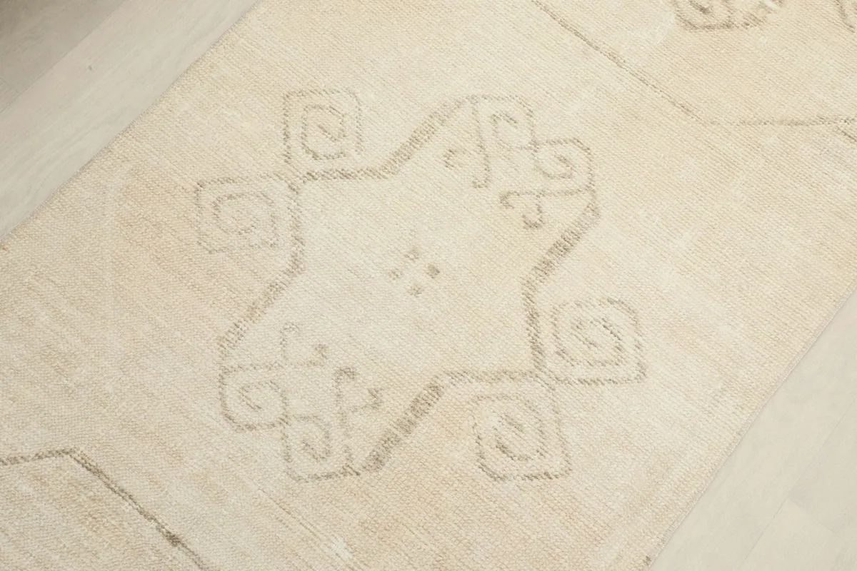 Detailed shot of a central geometric motif on the ivory runner, showcasing the faded beige design