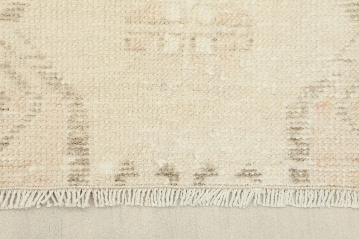 Close-up of the fringe and edge of the ivory runner, revealing the wool pile and cotton foundation