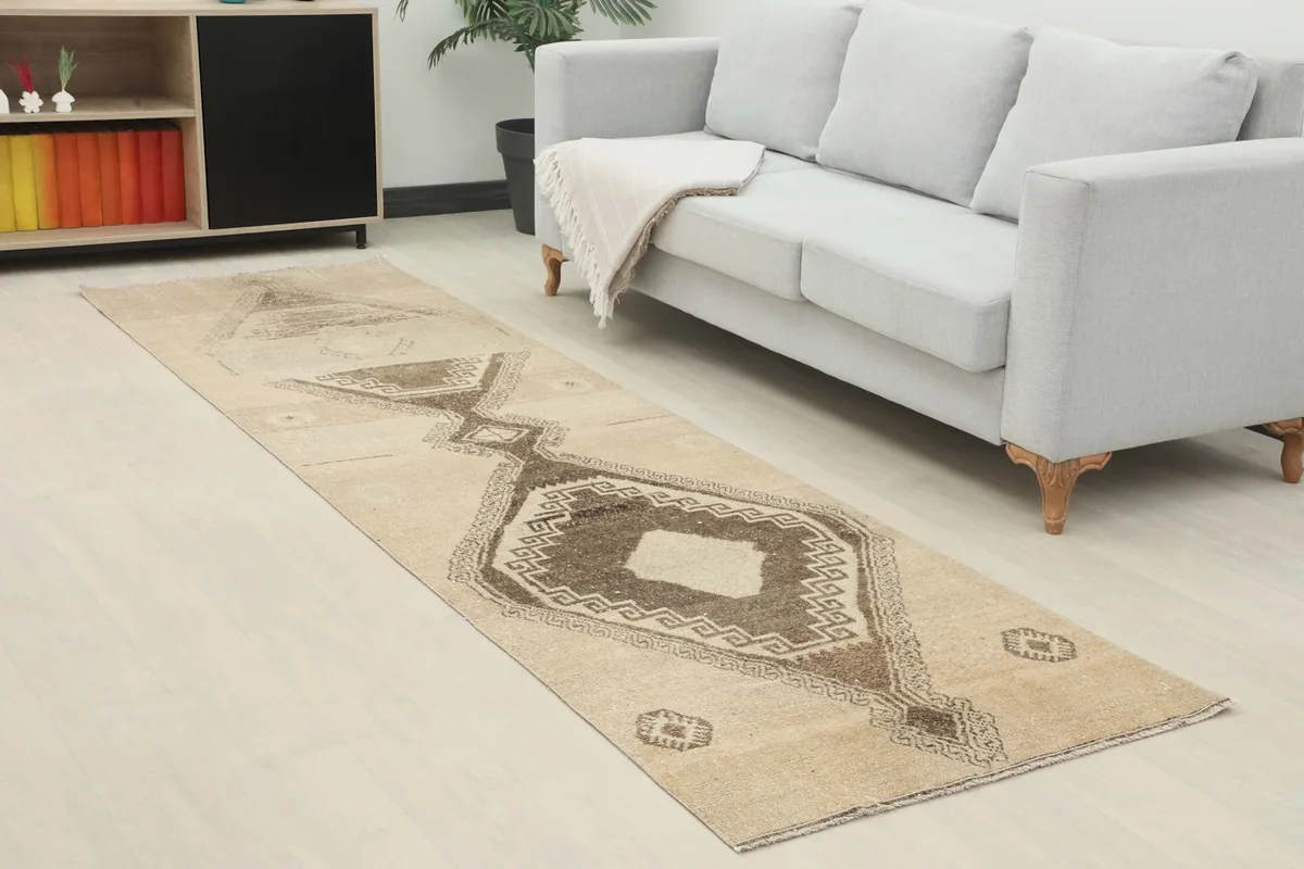 Vintage Anatolian runner rug in a living room setting, extending from a light-colored sofa.