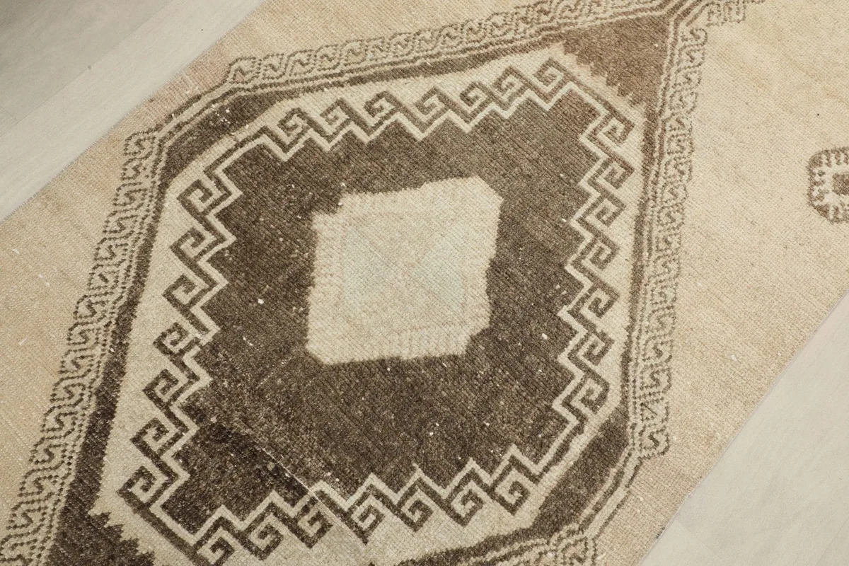 Detailed view of a central brown diamond motif with a lighter beige center and intricate border.