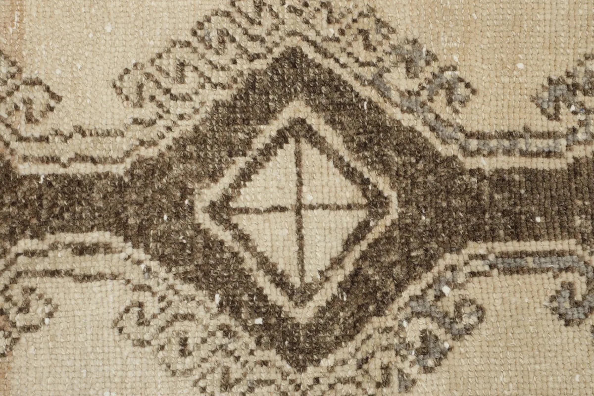 Macro shot of the wool pile showing texture and coloration within a brown geometric design.