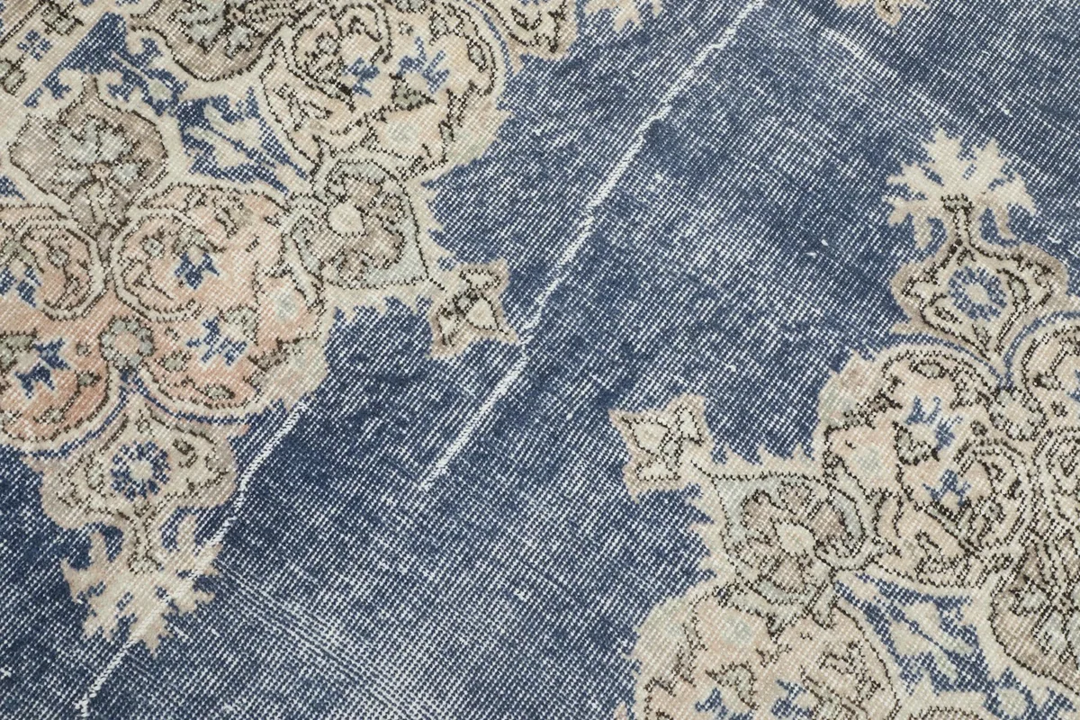 Close-up detail of the faded blue field and cream medallion motif with wear