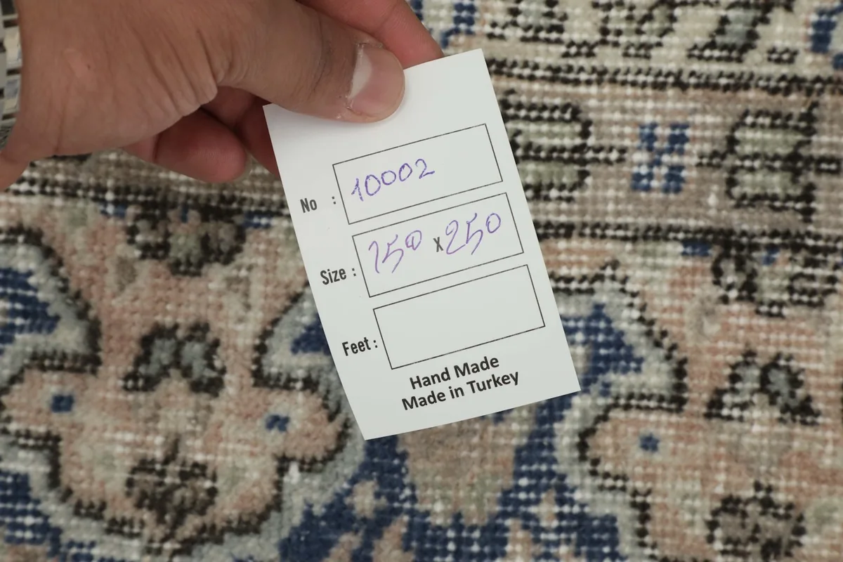Hand holding a tag showing rug number and size in centimeters