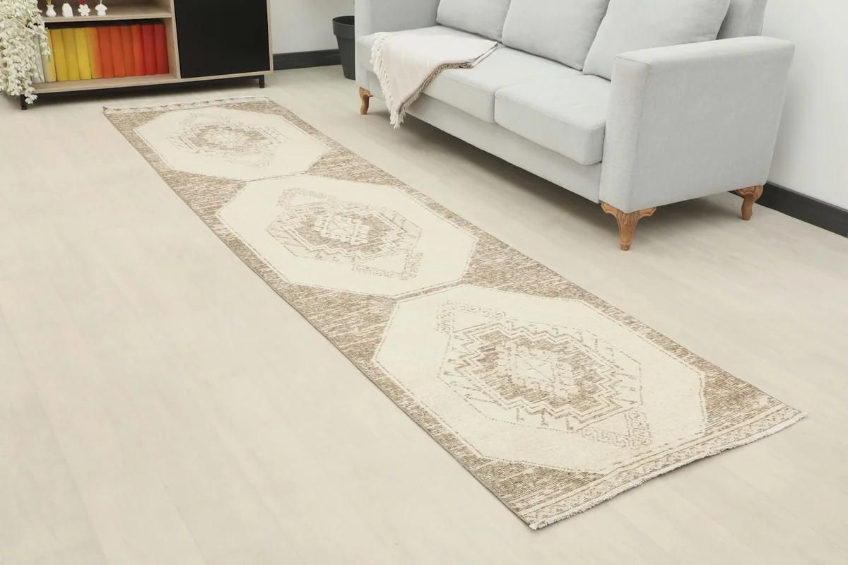 Long view of the beige runner rug laid out in a room, showing its full length and pattern