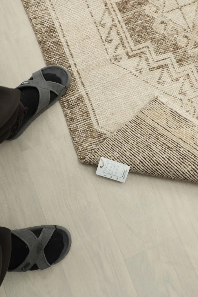 Feet in sandals next to the rug, showing scale and the vintage tag on the back
