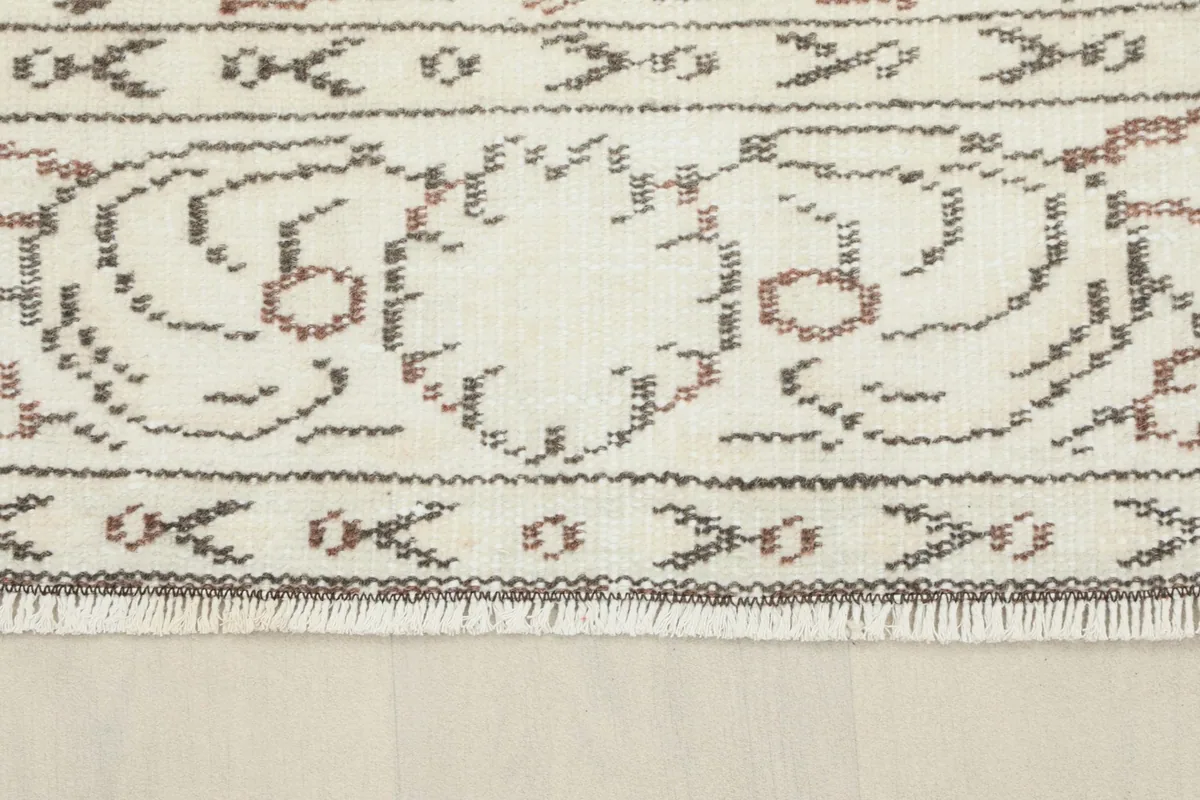 View of the rug's edge, displaying the short, natural fringe and the woven border details.