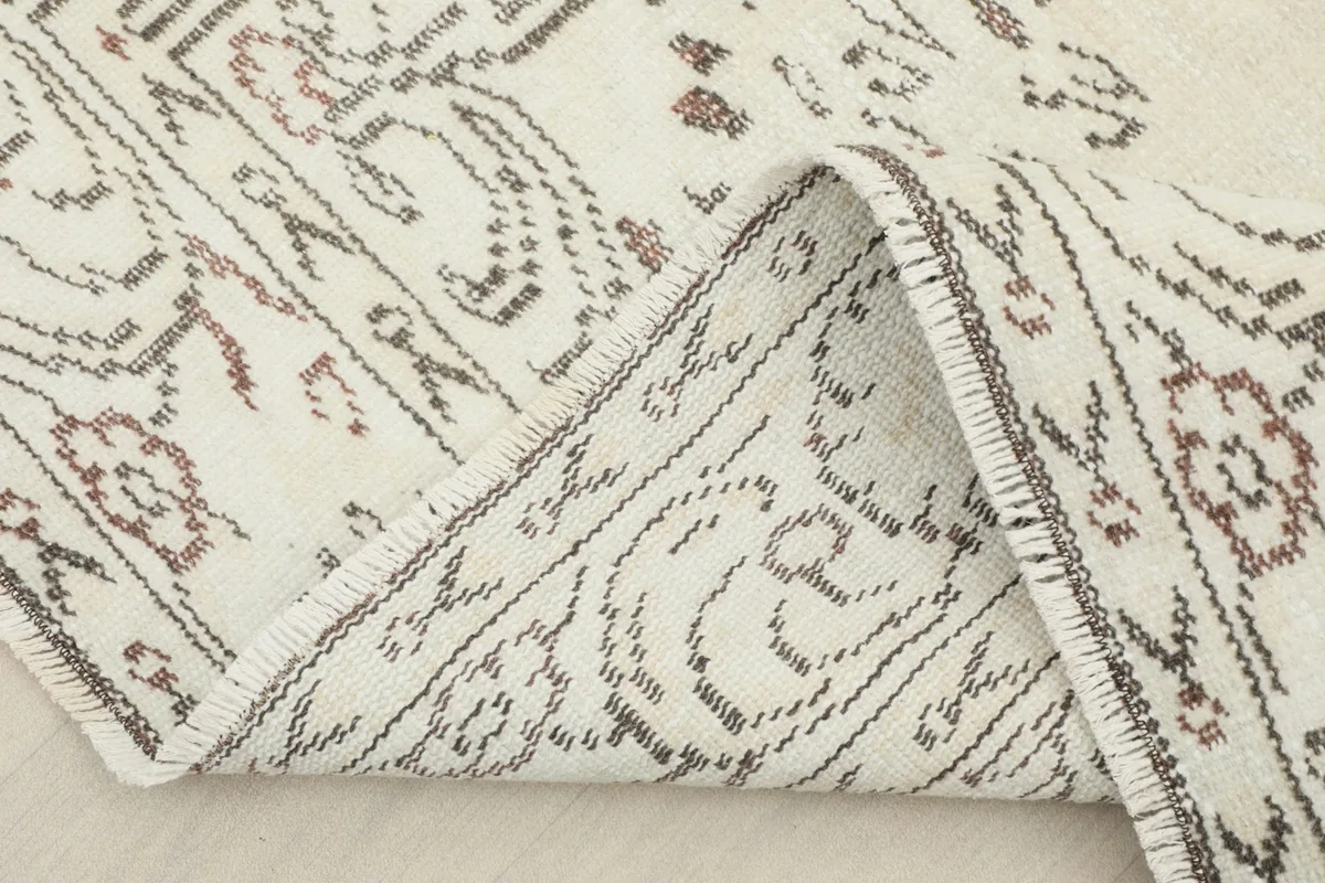 Folded corner of the rug, revealing the wool pile and cotton foundation structure from the reverse side.
