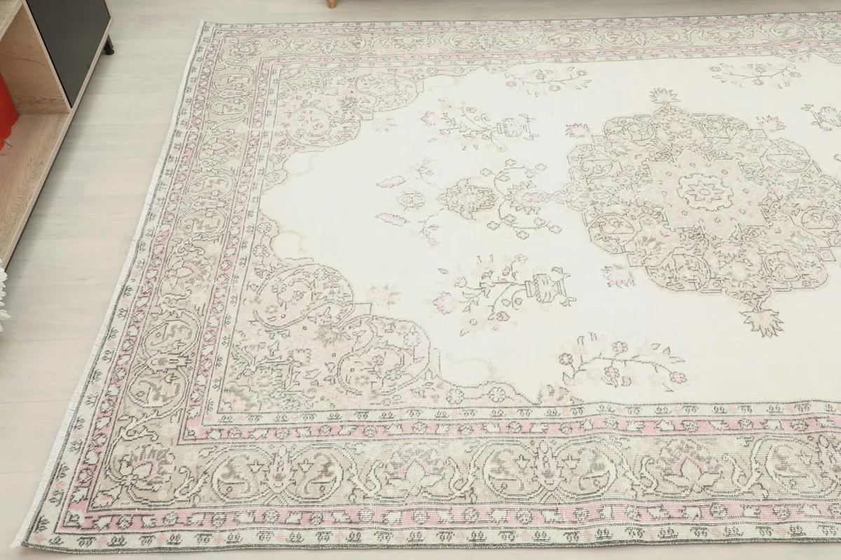 Corner angle of the ivory pink rug, showing the border design and color variations