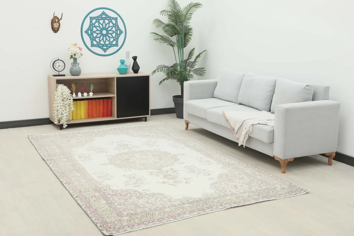 Ivory pink vintage rug placed in a living room setting with a light gray sofa
