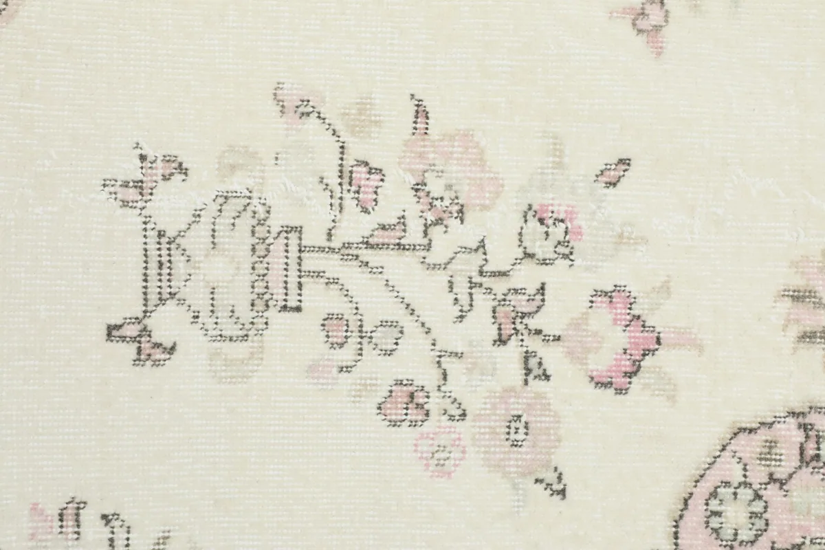 Close-up of a floral motif with pink accents on the ivory field of the rug