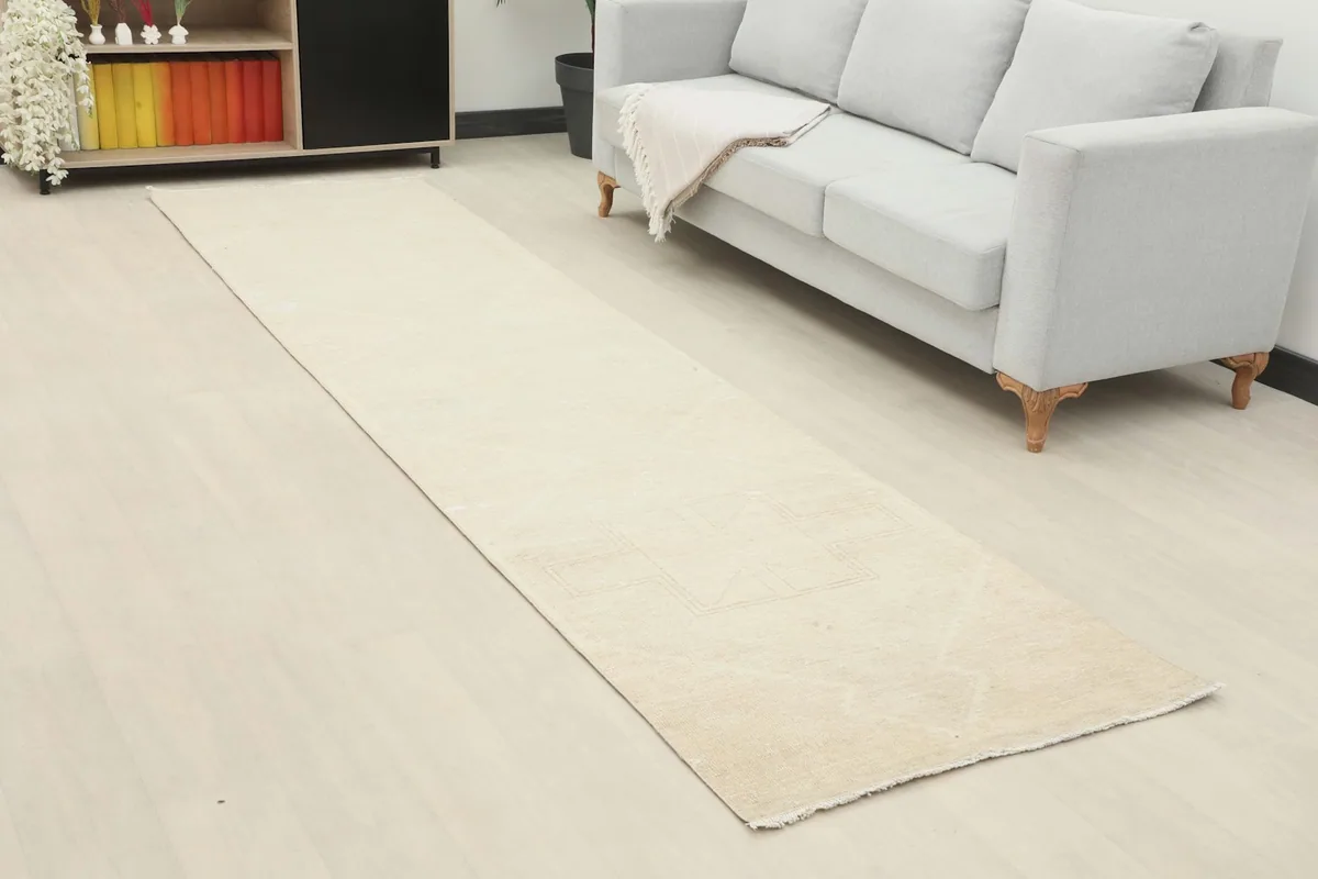 Close-up view of the beige vintage runner rug extending along the floor next to a light sofa.