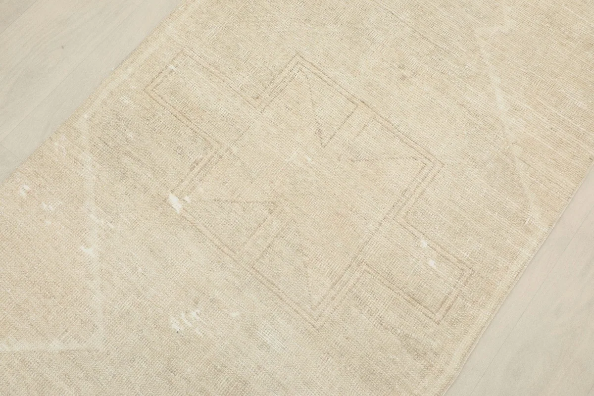 Overhead detail of the beige runner rug, highlighting a subtle geometric motif in the center.