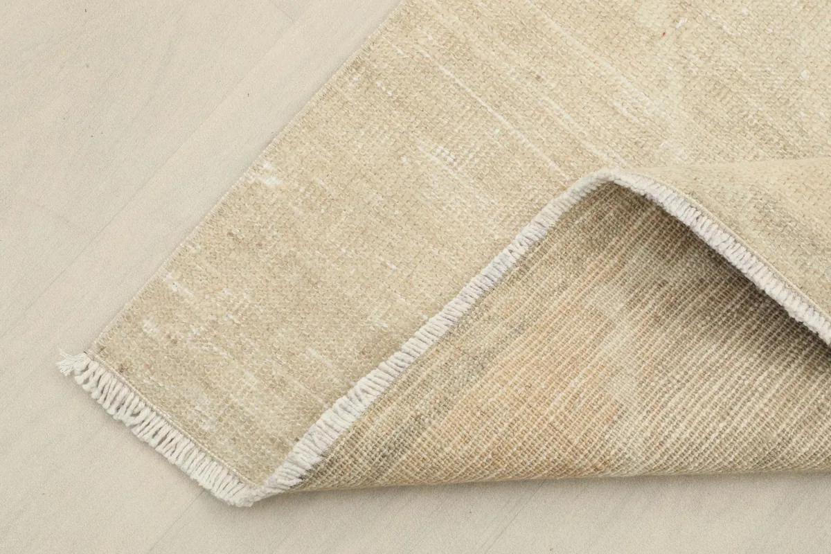 Corner of the rug folded to show the cotton foundation and reverse side of the hand-knotted runner.
