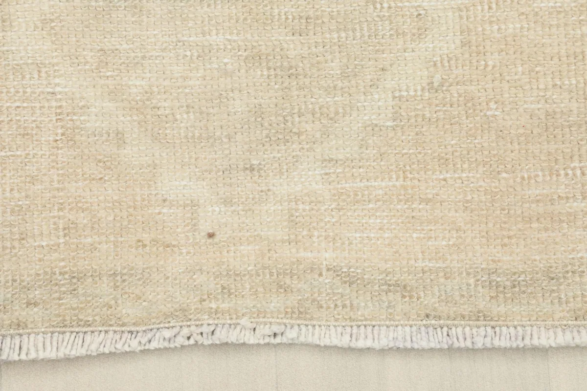 Detail of the short, natural fringes and the edge finish of the beige vintage runner.