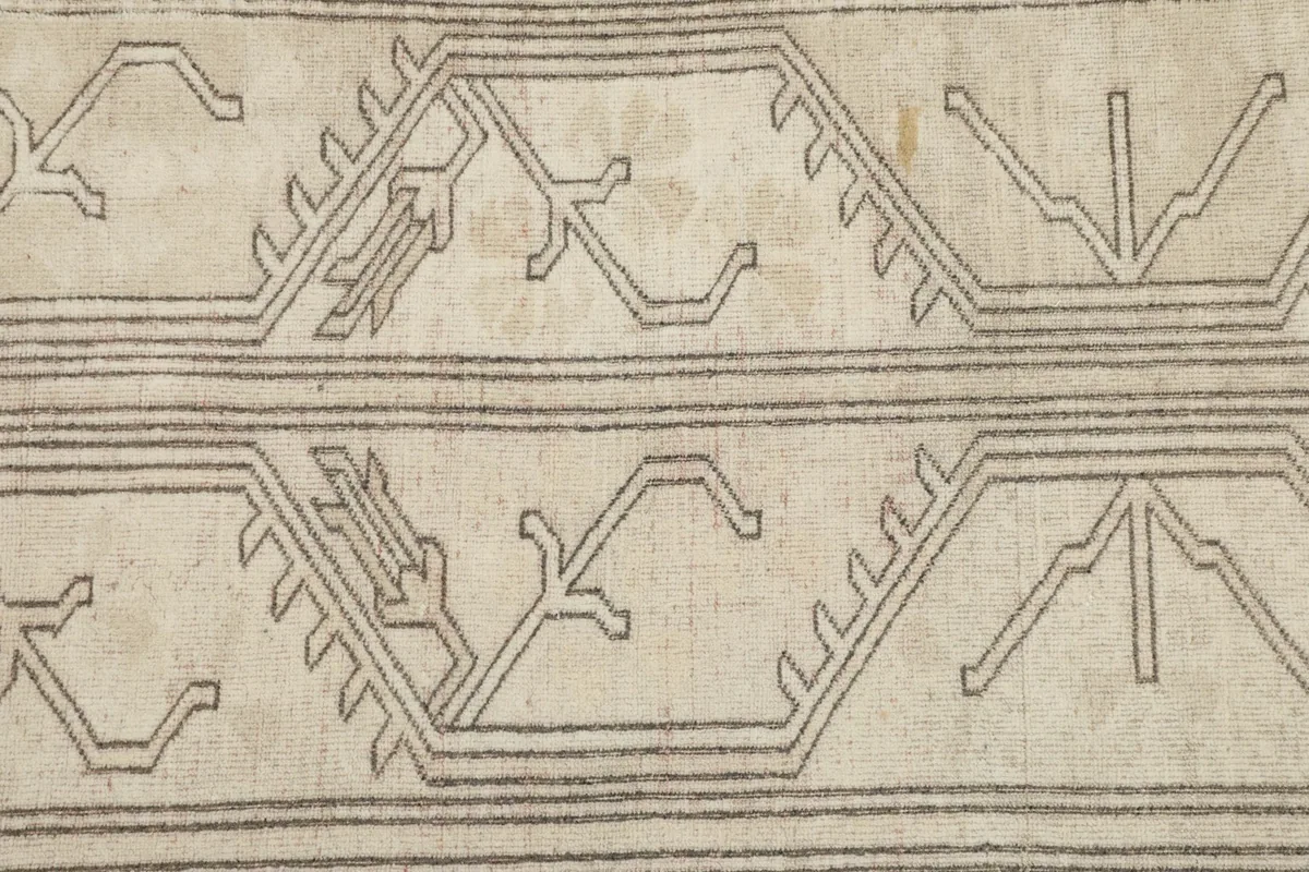 Close-up detail of the gray geometric and tribal patterns within the border design of the rug.