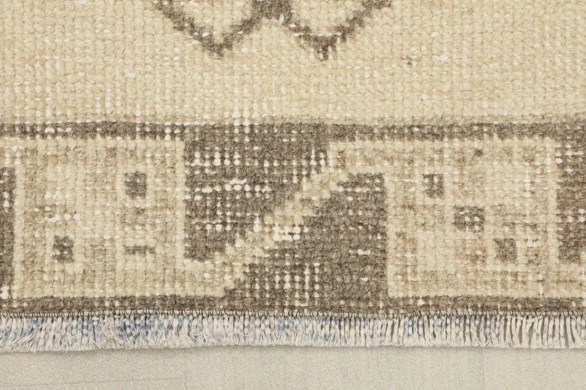 Detail of the short fringe and the edge of the hand-knotted wool rug, showing minor wear