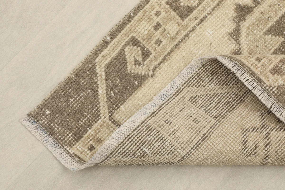 Corner of the runner folded to show the back of the rug and the texture of the cotton foundation