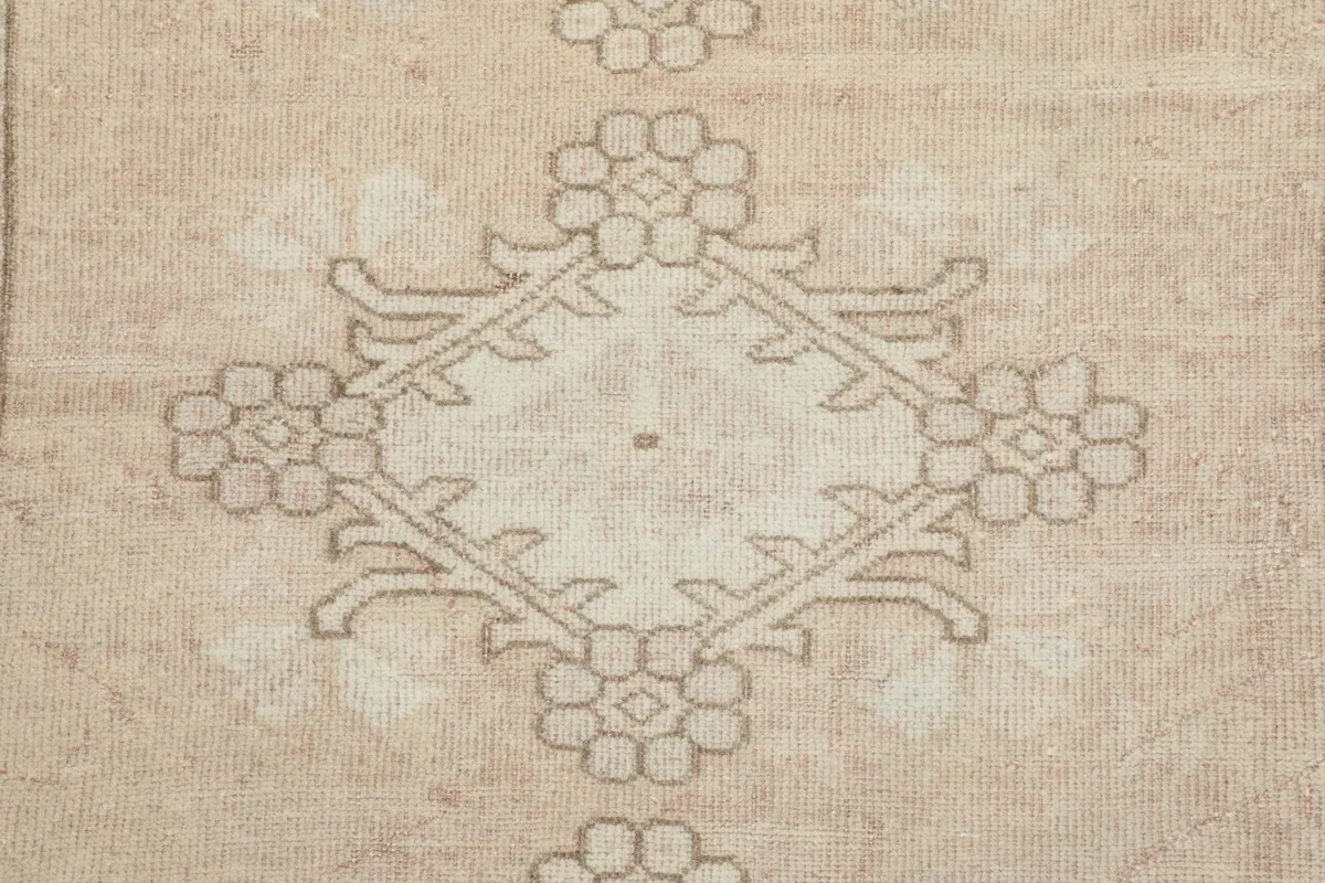 Detailed view of a central floral medallion motif within the rose field of the rug