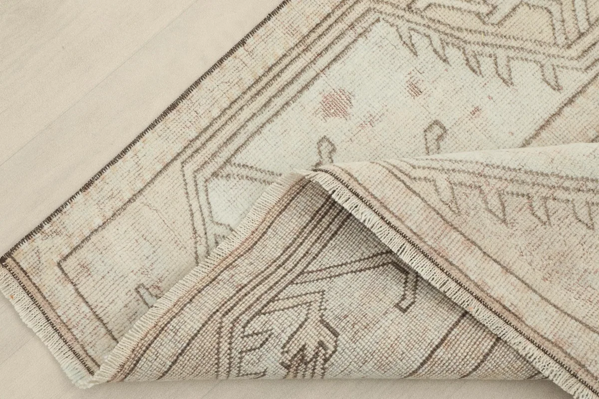 Folded corner of the rug revealing the wool pile and cotton foundation structure