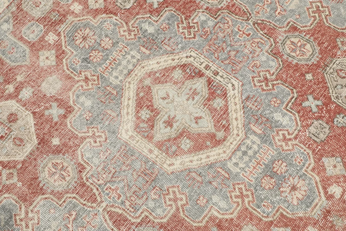 Close-up of a central geometric medallion motif in rust, gray, and ivory