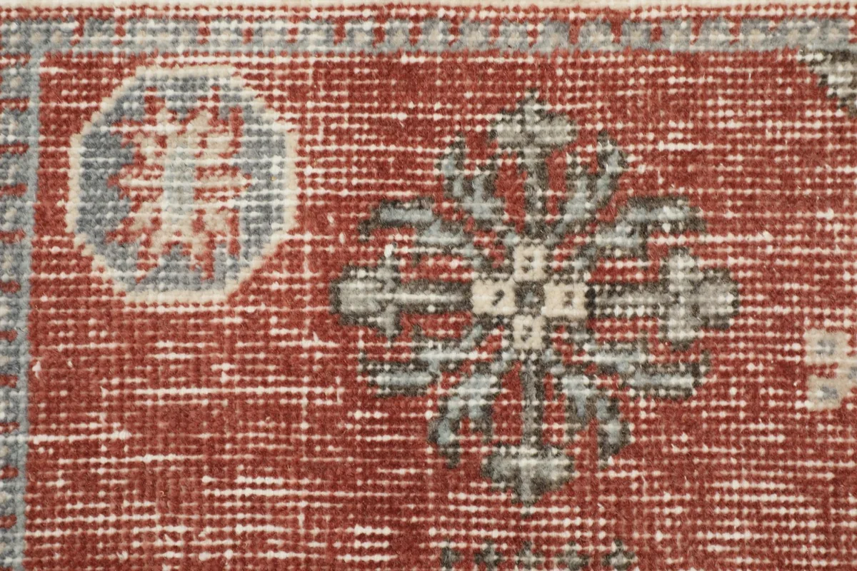 Detailed view of the rug's rust field and faded geometric designs