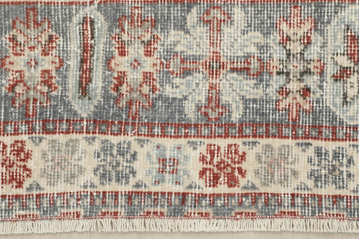 Close-up of the rug's border with floral and geometric elements and fringe