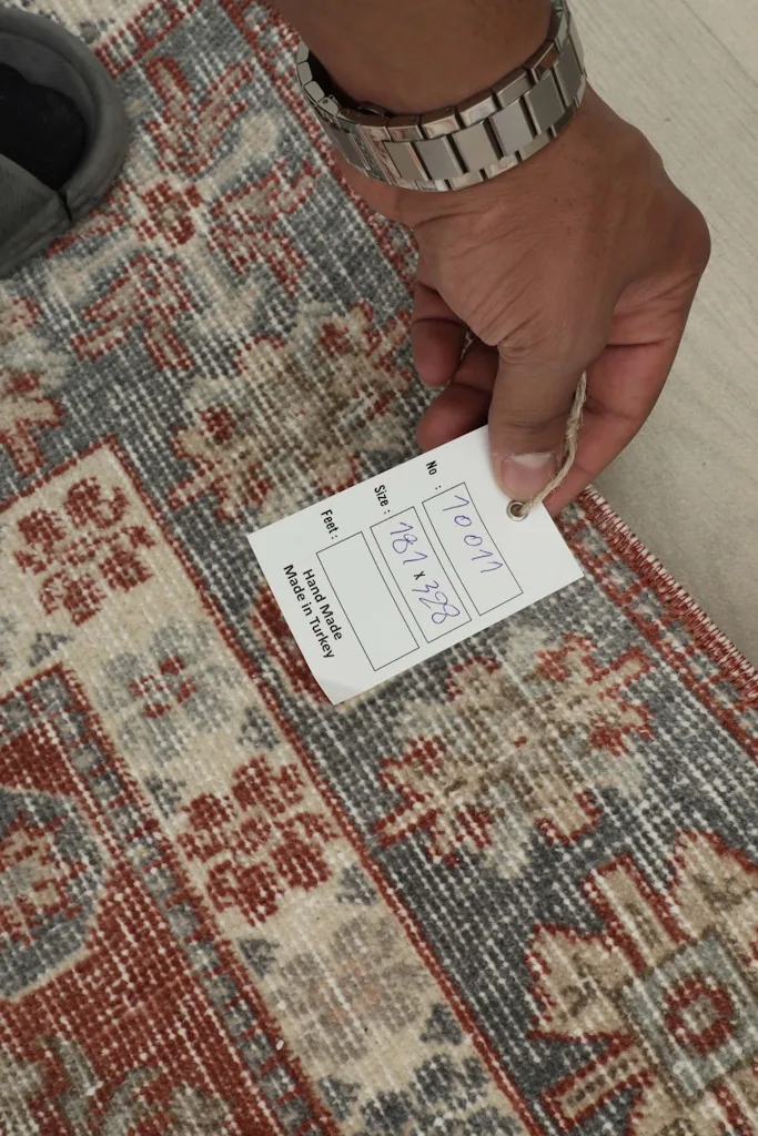 Hand holding a tag showing the rug's size 181x328 cm and origin Turkey