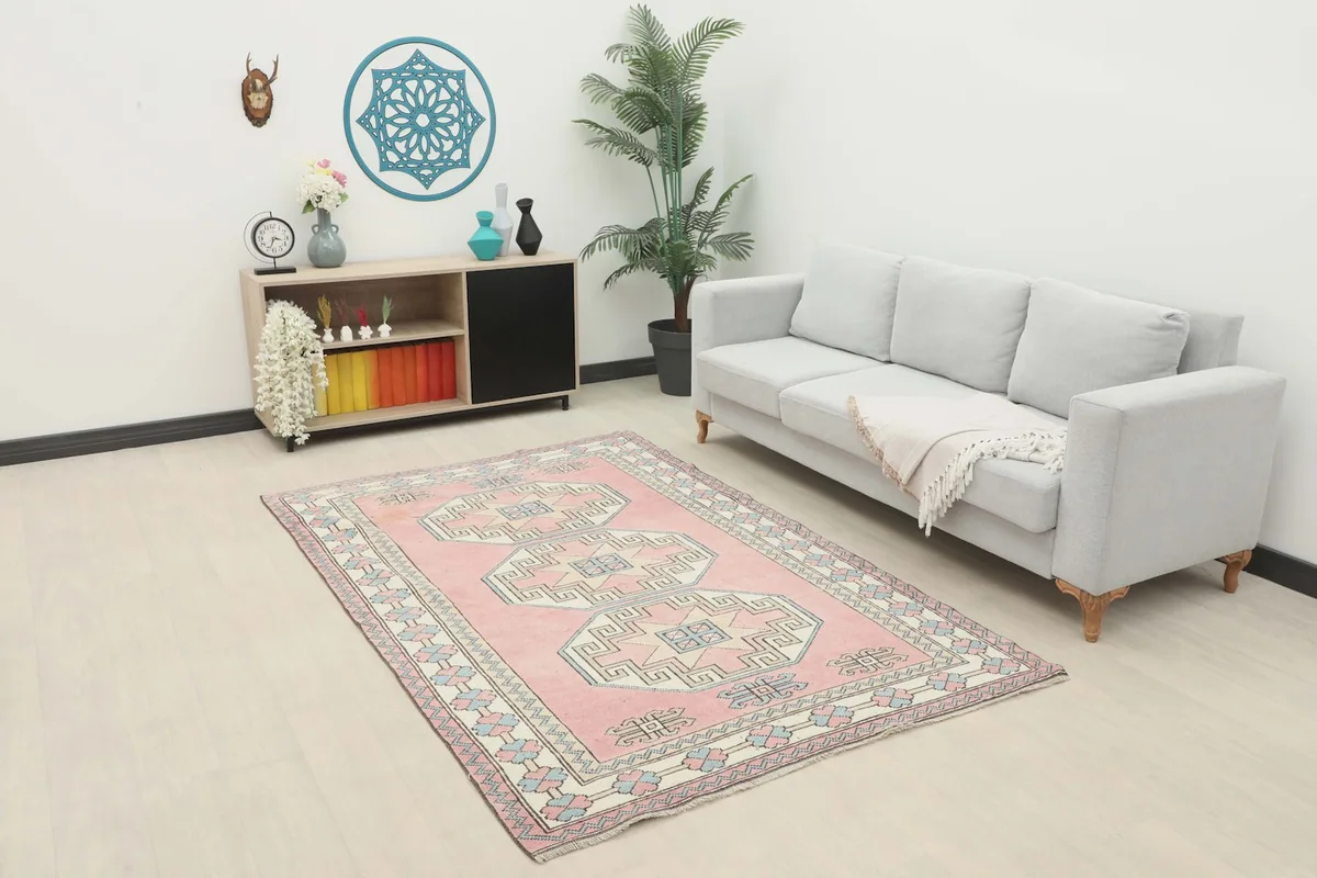 Pink geometric area rug displayed in a living room setting with a light gray sofa