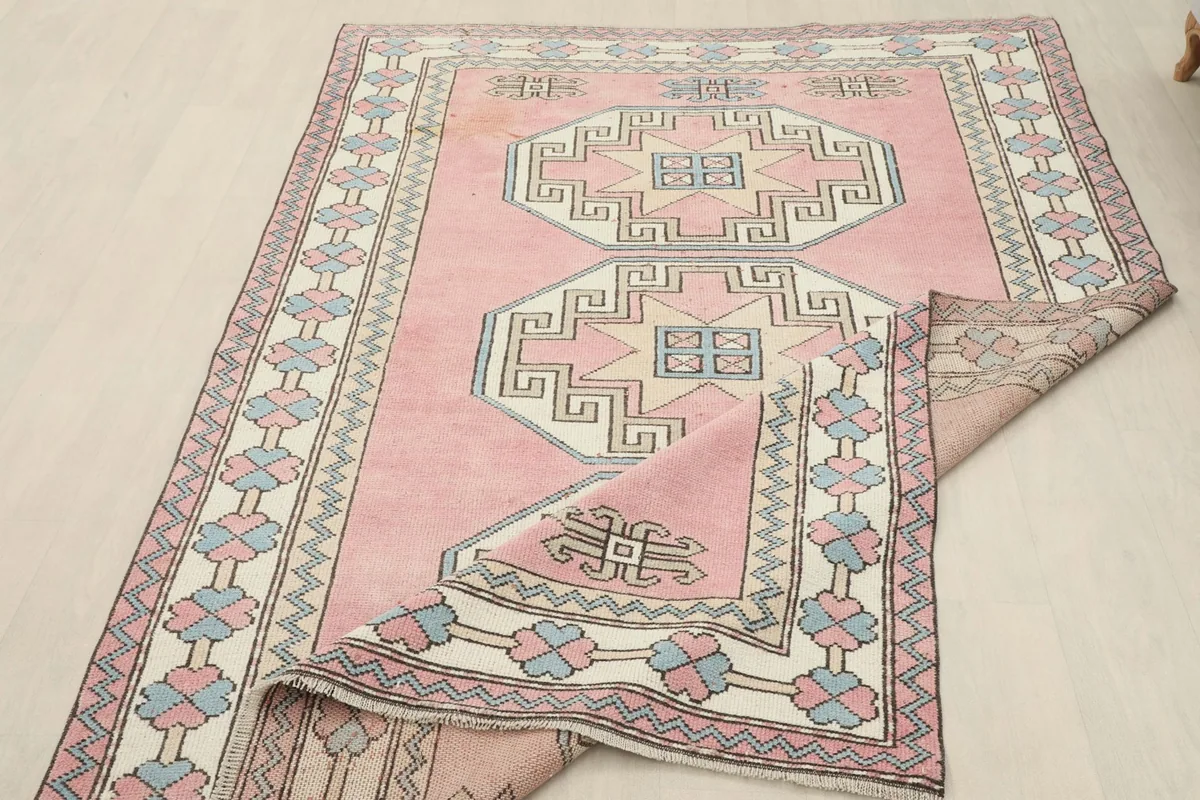 Partial view of the rug with a corner folded back, revealing the backing and design details