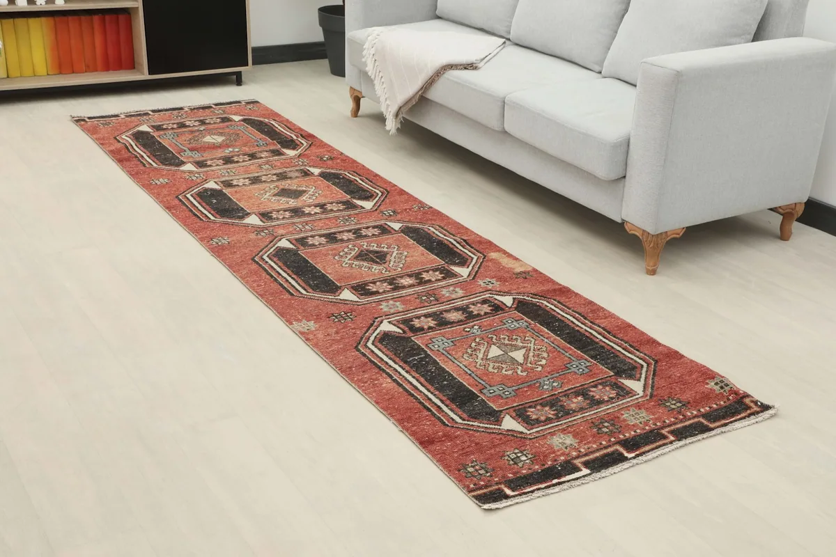 Angled view of the rust and black geometric runner rug in a modern living space with a couch.