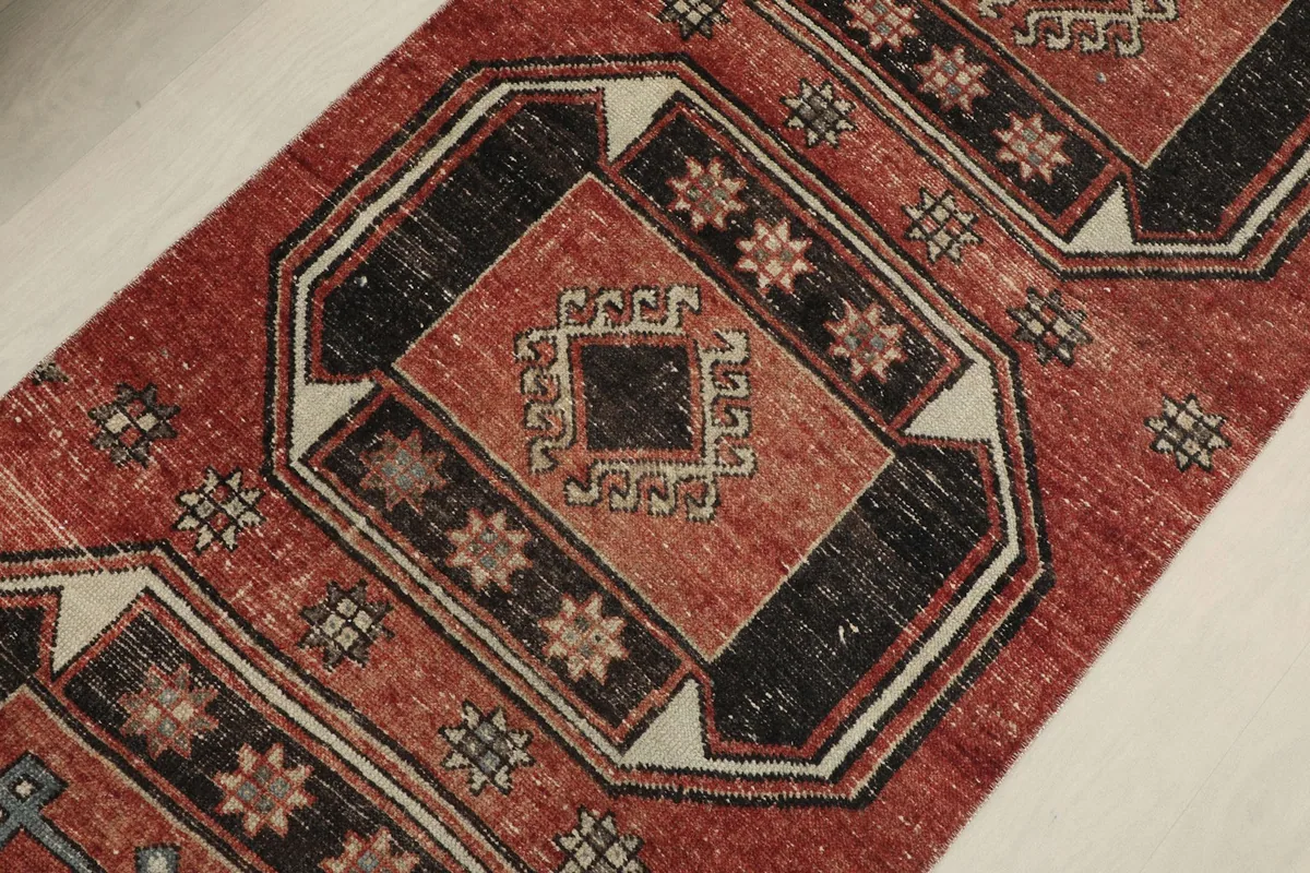Detailed view of a central geometric medallion on the rust runner rug, featuring black and beige elements.