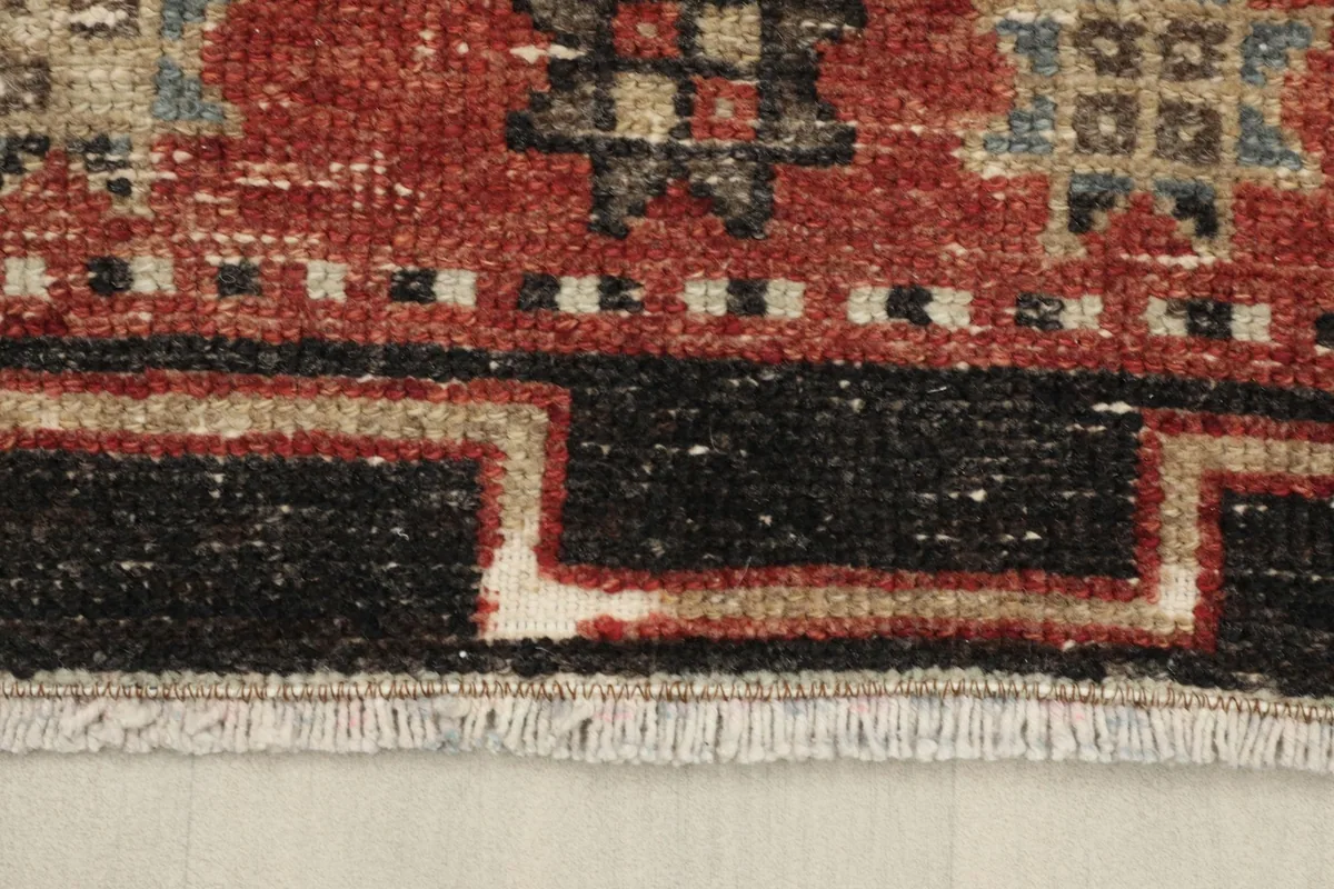 Close-up of the short fringe and the black and beige border design of the vintage Anatolian runner.