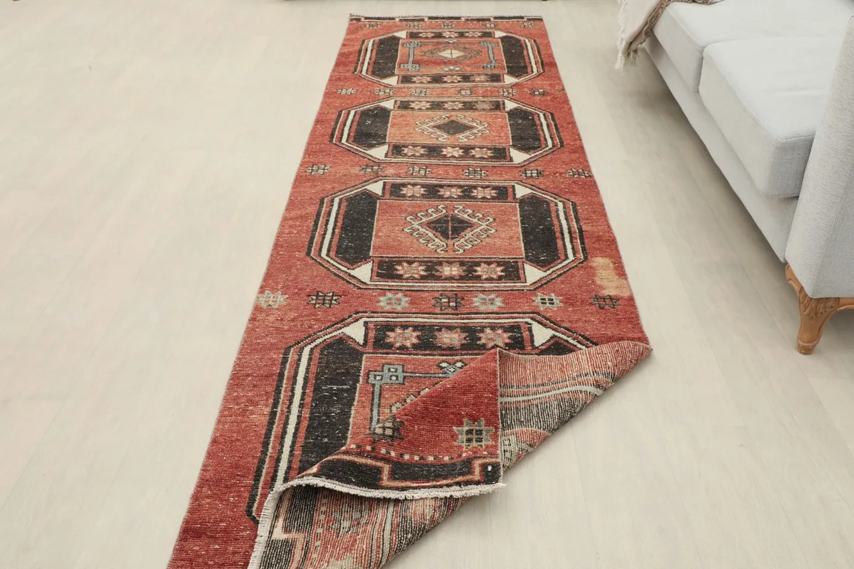 Runner rug partially folded, showing the full length and the reverse side, in a room setting.