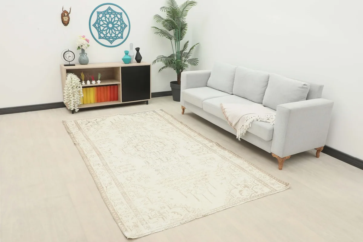 Cream and tan vintage rug laid out in a modern living room setting with a light gray sofa.