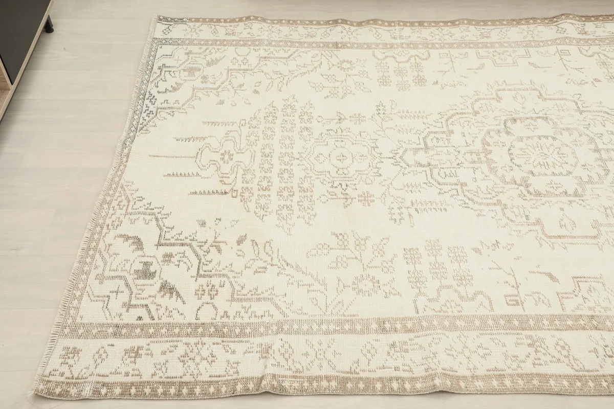 Detailed view of the rug's patterns and border from an angle, showing the subtle tan motifs.