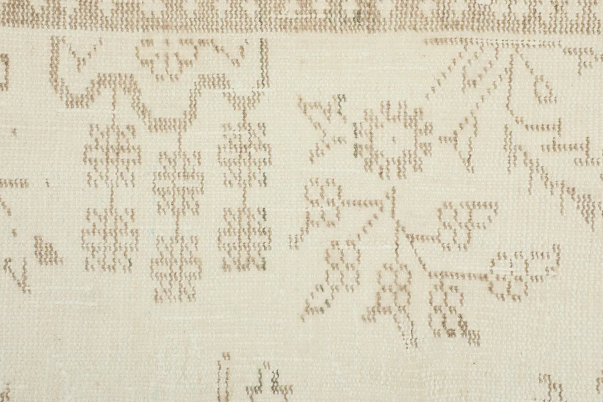 Close-up of the geometric and floral motifs within the field of the cream and tan rug.