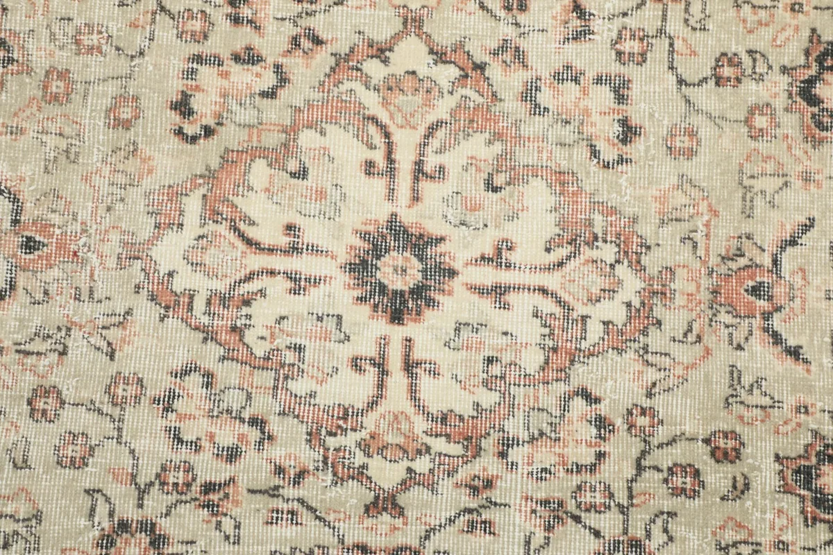 Detailed view of the central medallion, showing faded rose, gray, and ivory wool fibers.