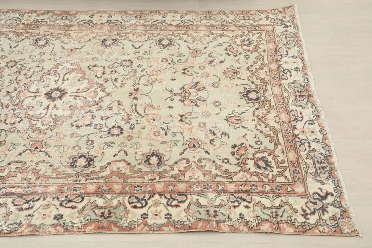 Close-up of the rug's border design, featuring rose and gray geometric and floral motifs.