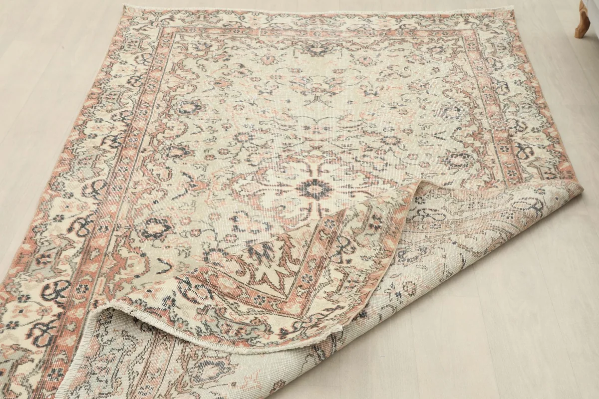The rug with a corner folded back, displaying the reverse side and the hand-knotted construction.