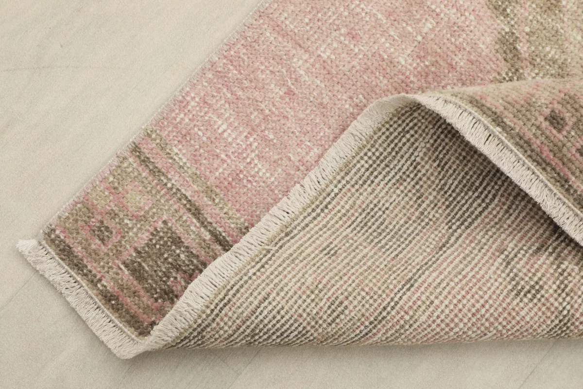 Folded corner showing the rug's back (cotton foundation) and the front (wool pile) with its tight weave.