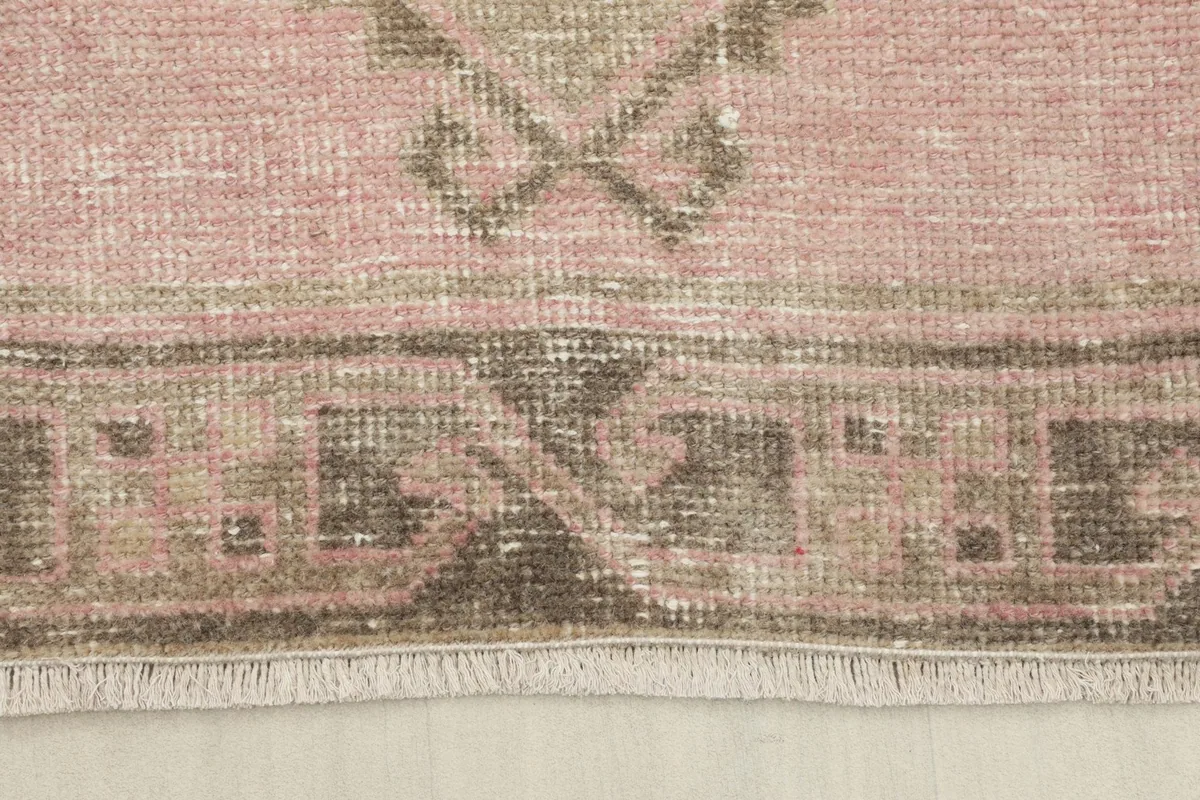 Close-up of the rug's end, showing the short, natural cotton fringes and the muted border design.