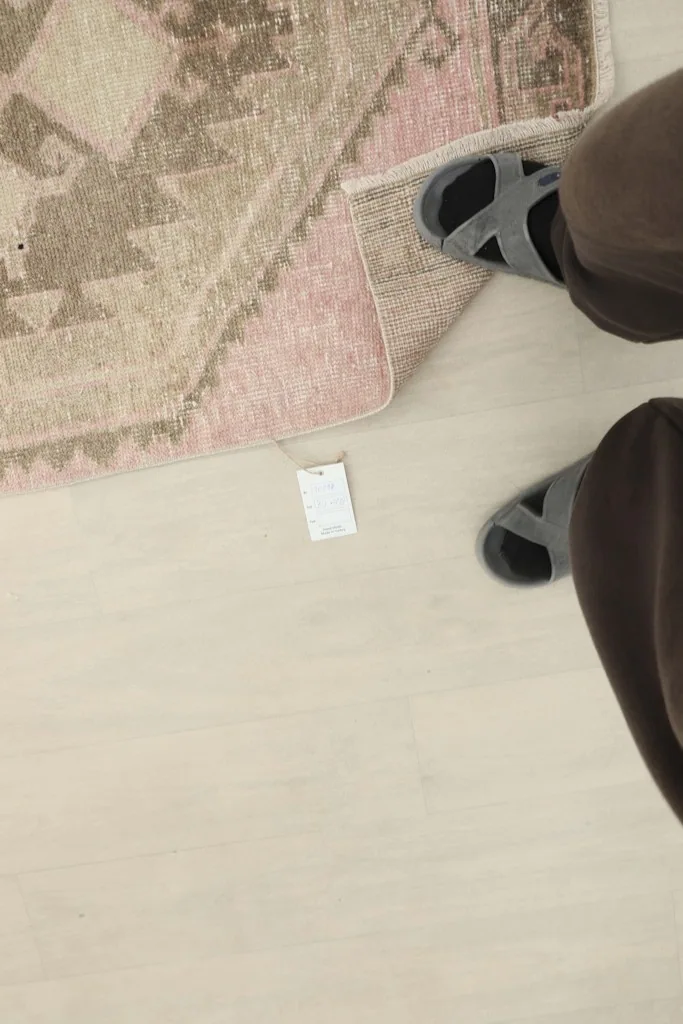 Overhead view of the rug's label next to a person's feet, showing the rug's scale and texture.