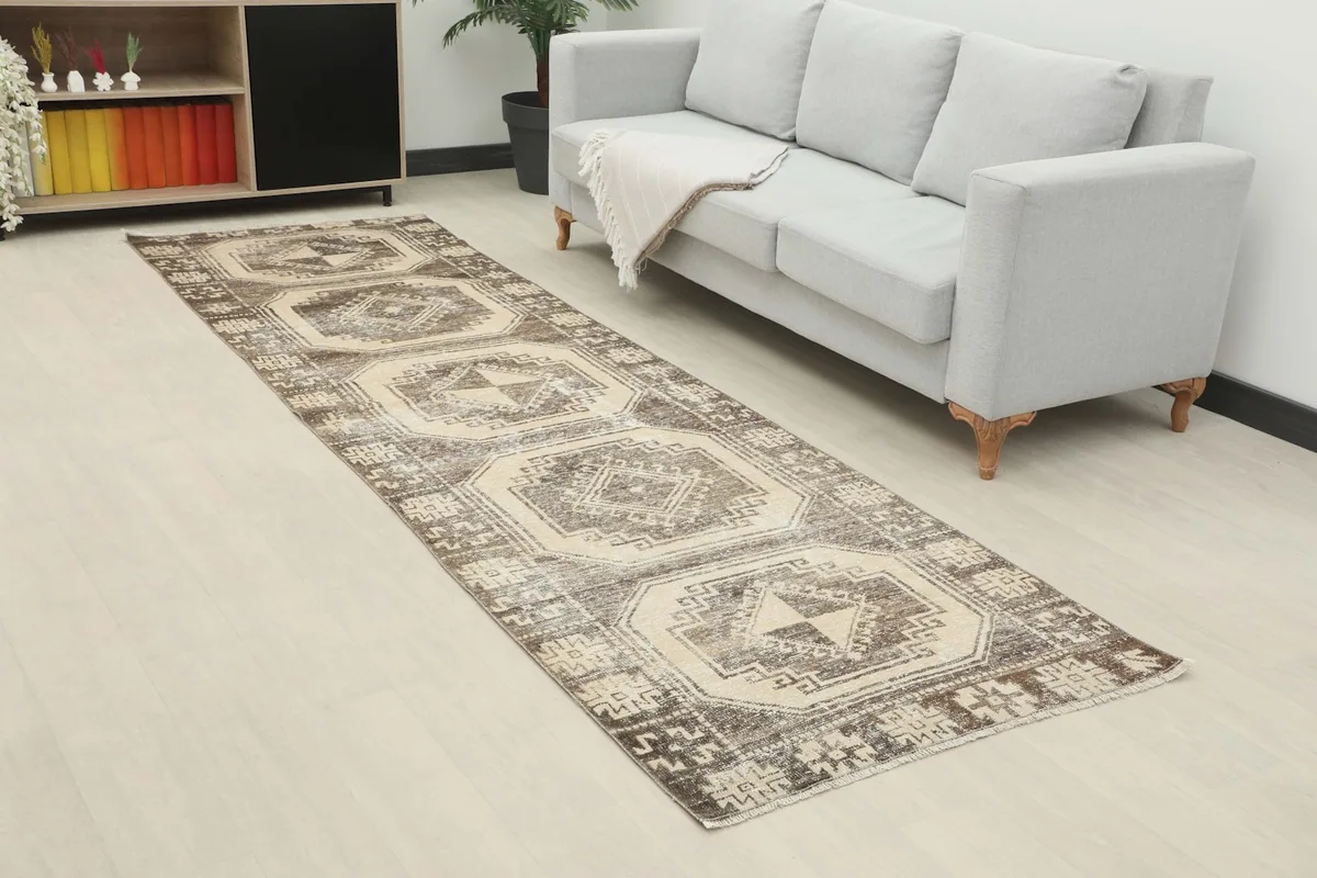 Overhead view of the brown and ivory runner rug in a room, showing its length next to a sofa.