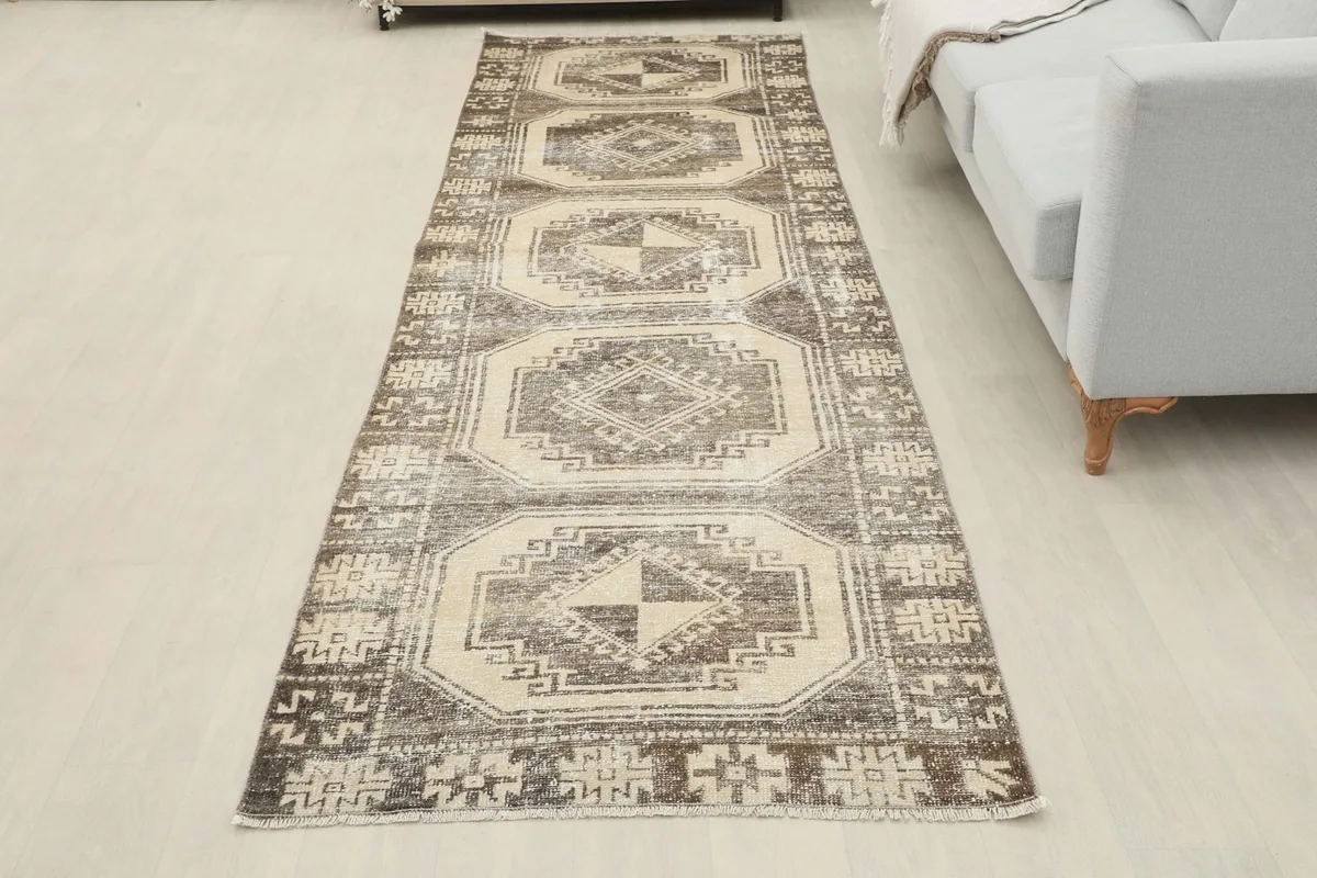 Full view of the brown and ivory runner rug laid out in a modern room setting.