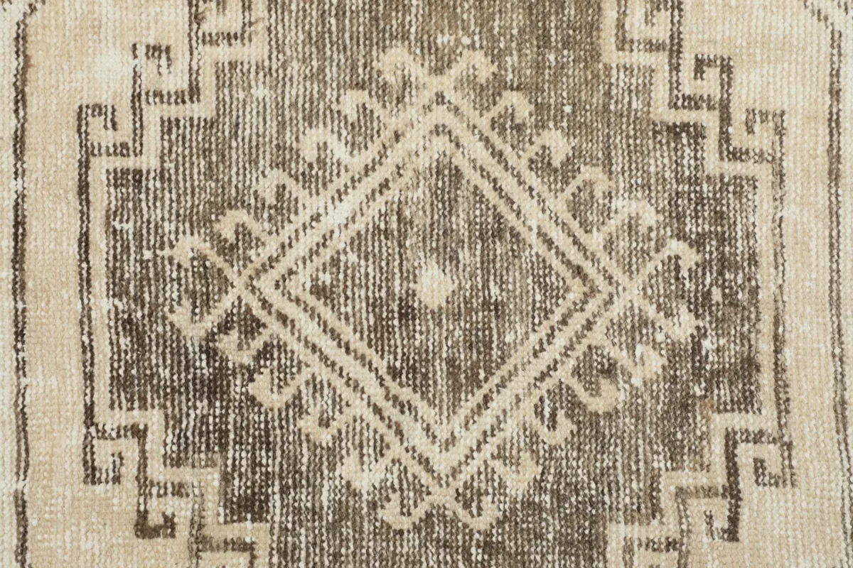 Close-up of the center of a geometric medallion, showing the faded wool pile texture.