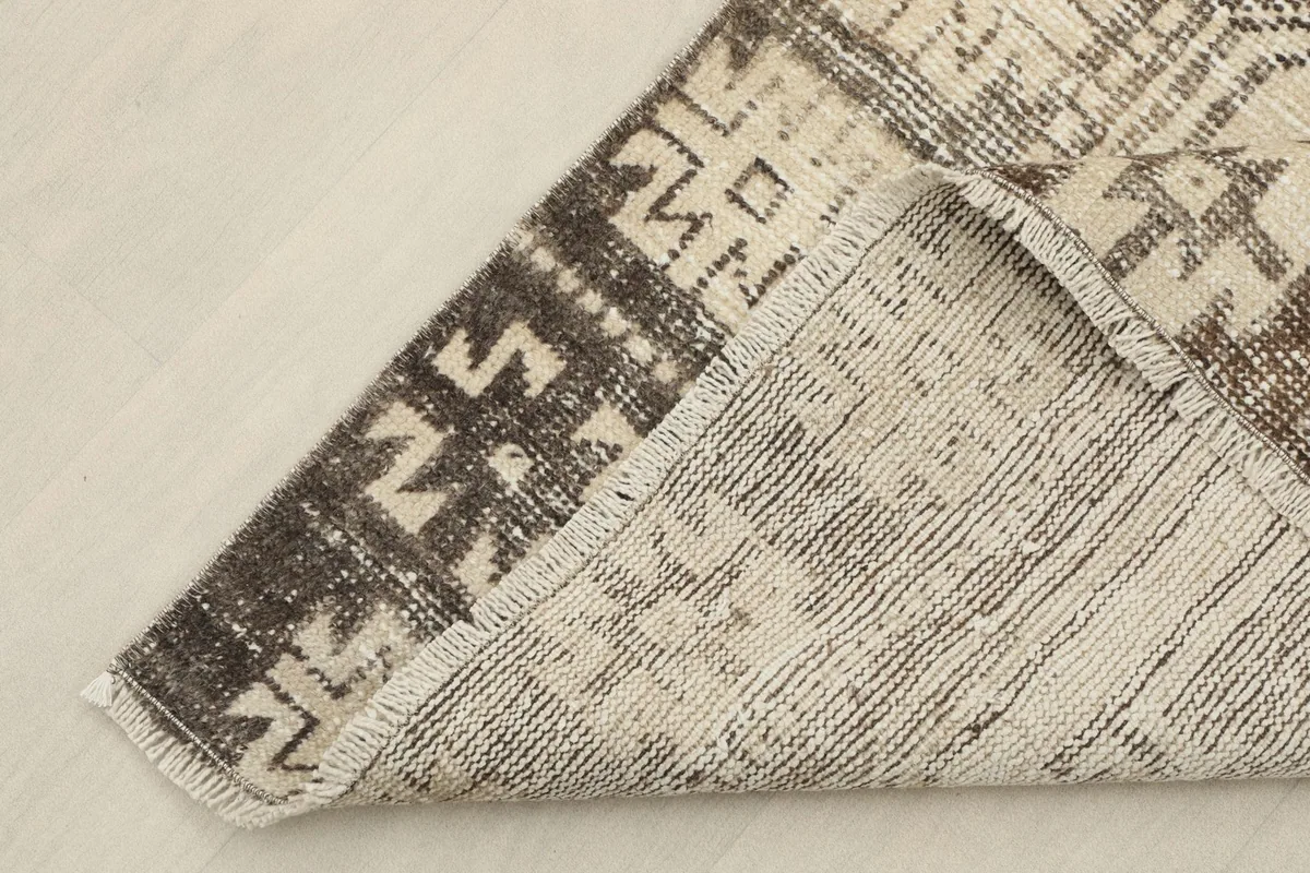 View of the back of a corner of the rug, showing the hand-knotted cotton foundation.