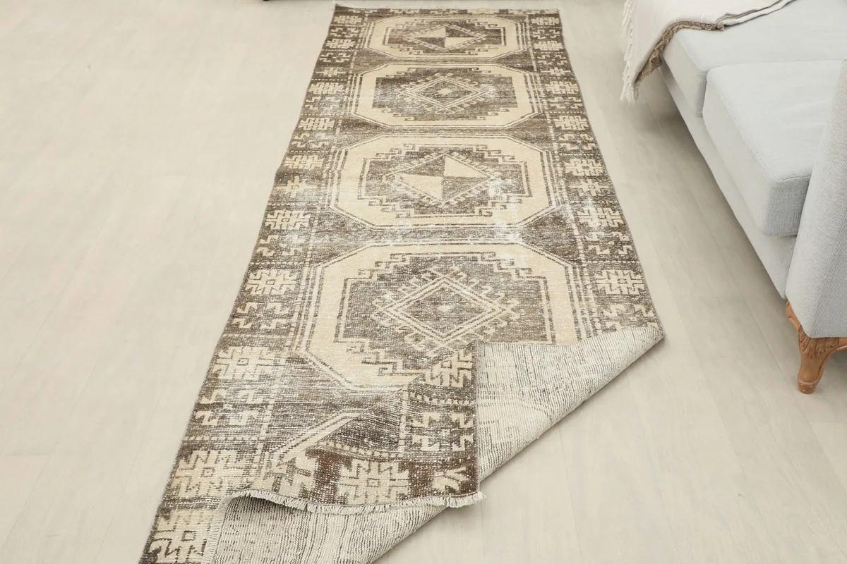 Runner rug with a corner folded back, revealing the back of the rug and the pile.