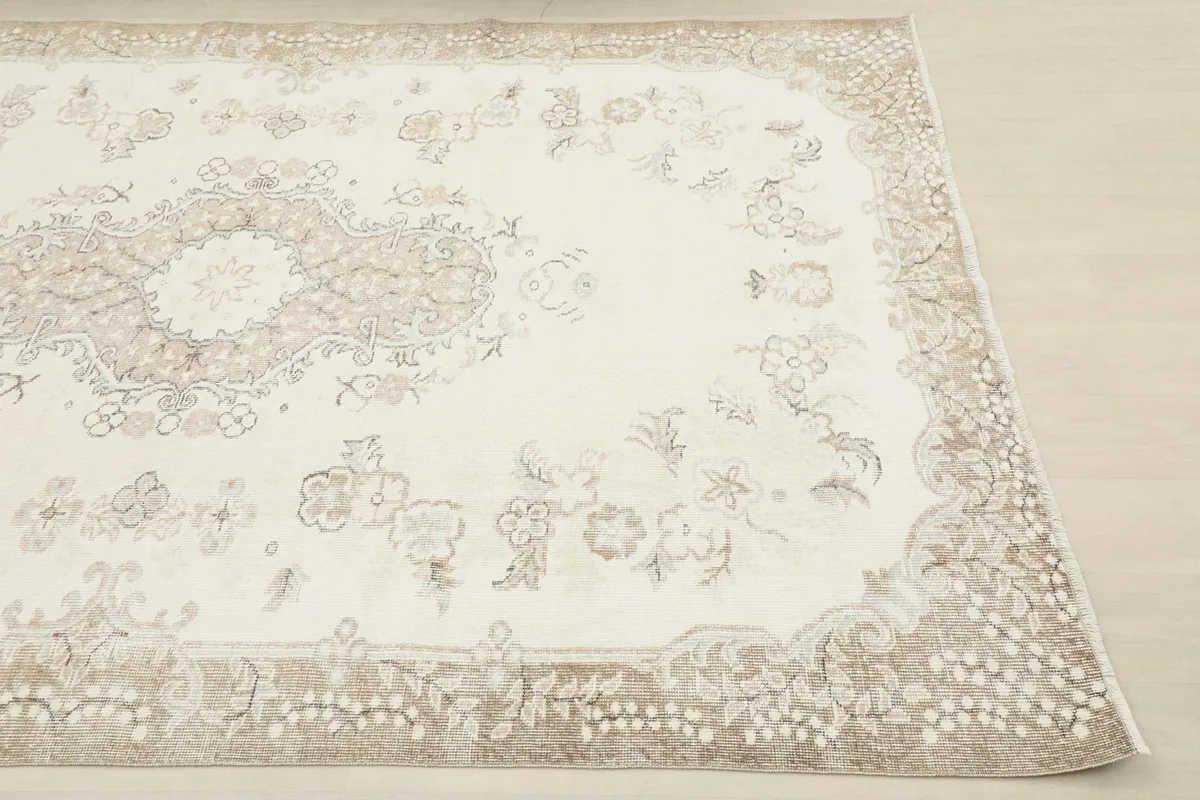 Corner view of the hand-knotted rug, highlighting the tan floral border pattern