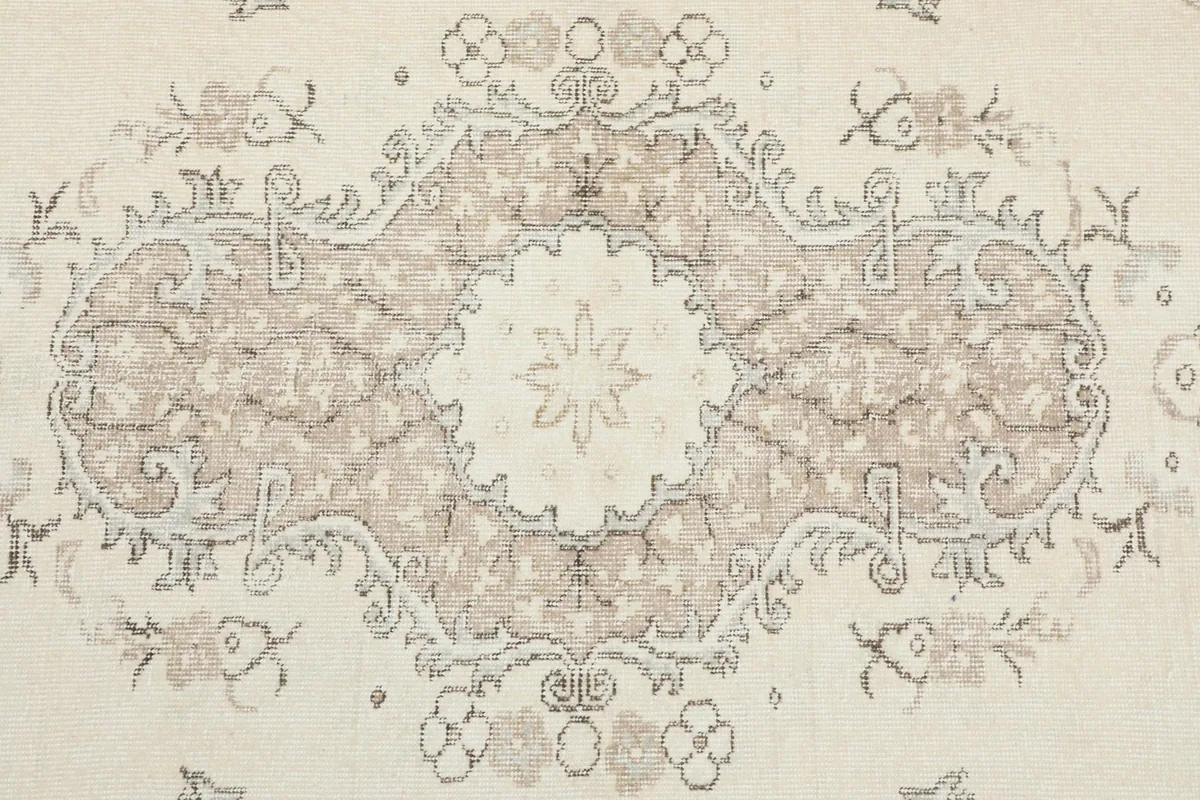 Close-up detail of the central tan medallion and surrounding floral patterns on the rug
