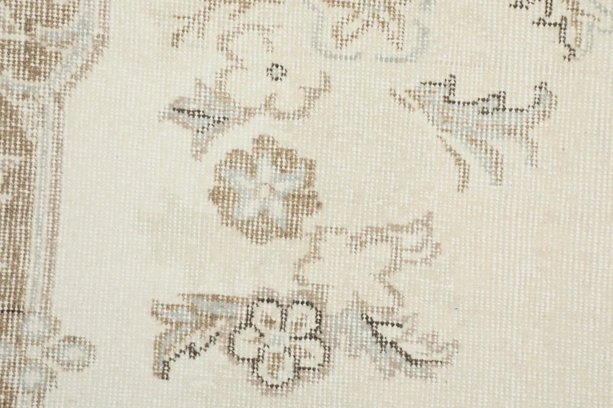 Detailed view of the individual floral motifs and subtle color variations on the ivory rug field
